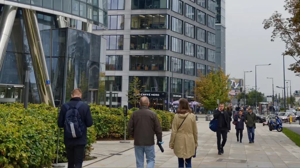 Profissionais caminhando no distrito de Zuidas em Amsterdam, ilustrando o ambiente de trabalho para o visto highly skilled migrant Holanda em 2026, com prédios modernos e bicicletas.